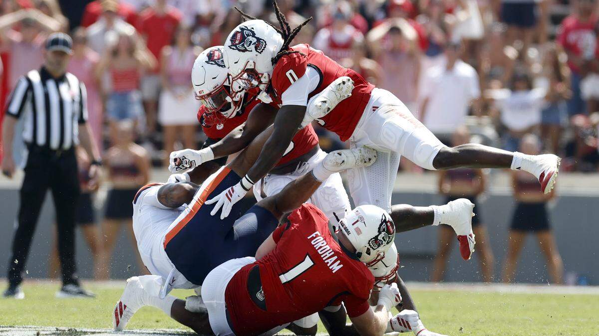 N.C. State’s Caden Fordham (1) and Sean Brown (0) tackle Virginia tight end Dakota Twitty (9) during the first half of N.C. State’s game against Virginia at Carter-Finley Stadium in Raleigh, N.C., Sat. Sept. 6, 2025.
