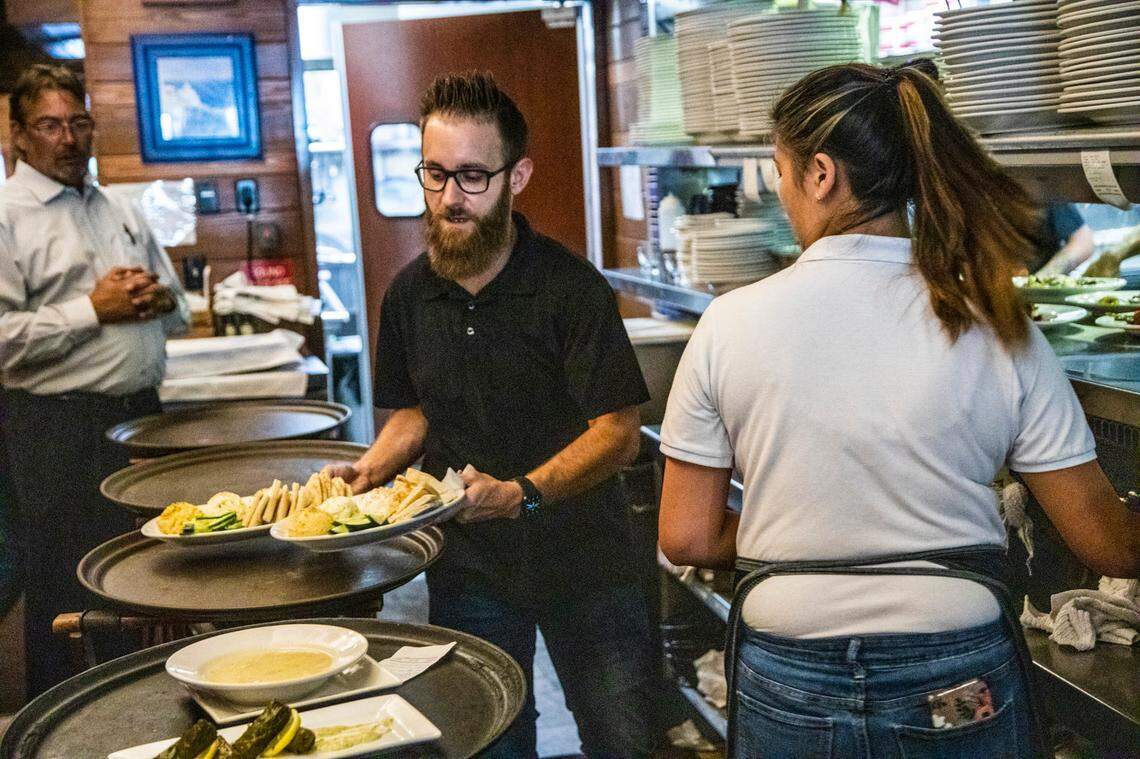 Food runner Lee Baine, center prepares to take food to diners Wednesday, June 16, 2021 at Taverna Agora Greek Kitchen & Bar in Raleigh. Many restaurants say business is starting to return to normal as coronavirus restrictions have lifted but hiring remains a challenge.