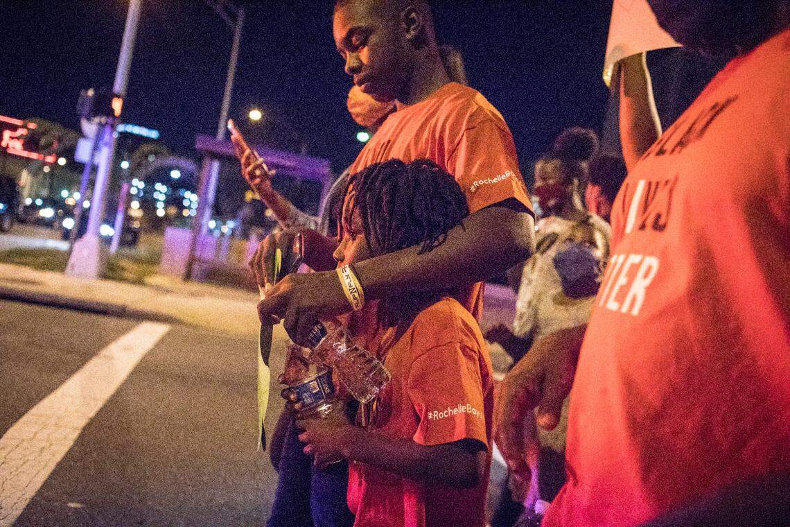 Jaylin Harris, 15, puts his arm around Zakarrayya Cornelius, 9, as they march with protesters through downtown Durham, N.C. on Friday, Sept. 4, 2020. Cornelius became worried as the group approached Durham police officers who were directing traffic in their patrol cars during the protest. Harris comforted him as they marched, and protesters, including their mothers, chanted their names.