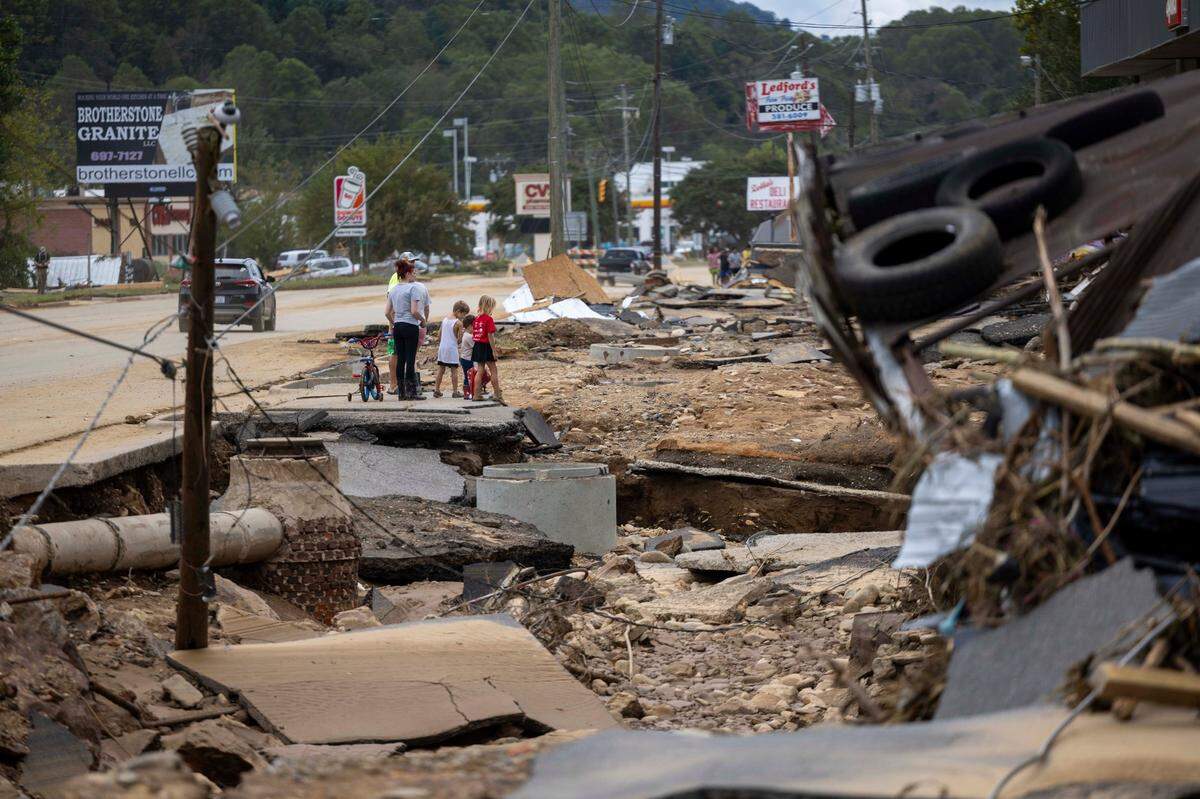 Swannanoa residents walk through devastating flood damage from the Swannanoa River on Sunday, Sept. 29, 2024. The remnants of Hurricane Helene caused widespread flooding, downed trees, and power outages in western North Carolina.
