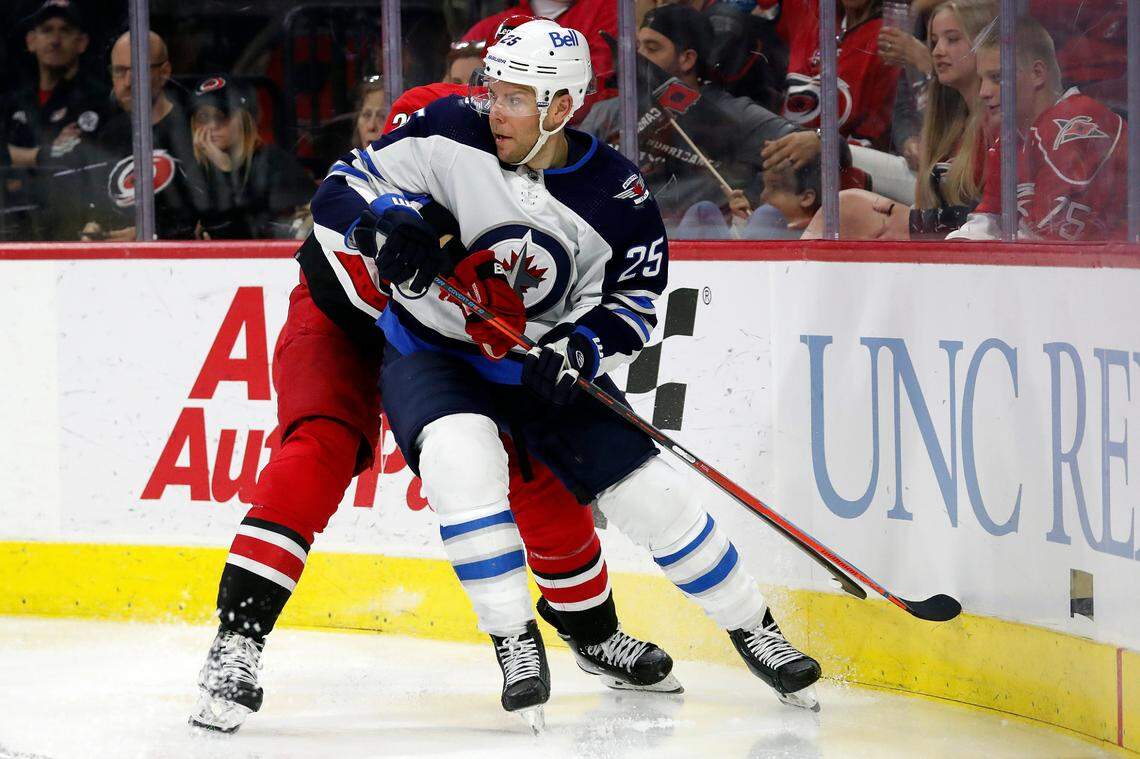Winnipeg Jets’ Paul Stastny (25) watches play as he battles with Carolina Hurricanes’ Brett Pesce (22) during the third period of an NHL hockey game in Raleigh, N.C., Thursday, April 21, 2022. (AP Photo/Karl B DeBlaker)