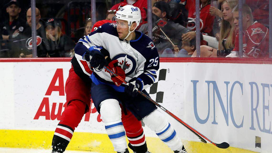Winnipeg Jets’ Paul Stastny (25) watches play as he battles with Carolina Hurricanes’ Brett Pesce (22) during the third period of an NHL hockey game in Raleigh, N.C., Thursday, April 21, 2022. (AP Photo/Karl B DeBlaker)