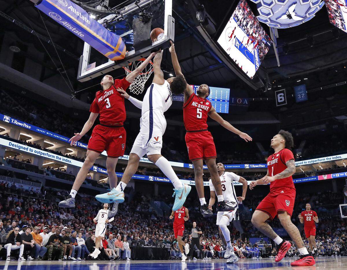 Virginia's Malik Thomas drives to the basket past N.C. State's Matt Able and N.C. State's Tre Holloman during the second half of the Wolfpack’s 81-74 loss in the ACC Tournament quarterfinals on Thursday, March 12, 2026, at the Spectrum Center in Charlotte, N.C. 