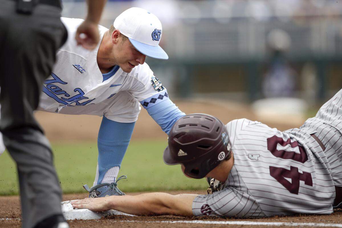 Mississippi State's Elijah MacNamee (40) slides back safely to first as North Carolina first baseman Michael Busch (15) makes the tag in the second inning of an NCAA College World Series baseball game in Omaha, Neb., Tuesday, June 19, 2018.
