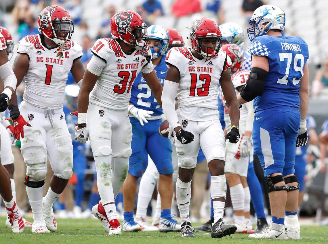N.C. State linebacker Isaiah Moore (1) and Vi Jones (31) celebrate with N.C. State defensive back Tyler Baker-Williams (13) after Baker-Williams stopped Kentucky for a loss during the second half of Kentucky’s 23-21 victory over N.C. State in the Gator Bowl at TIAA Bank Field in Jacksonville, Fla., Saturday, January 2, 2021.