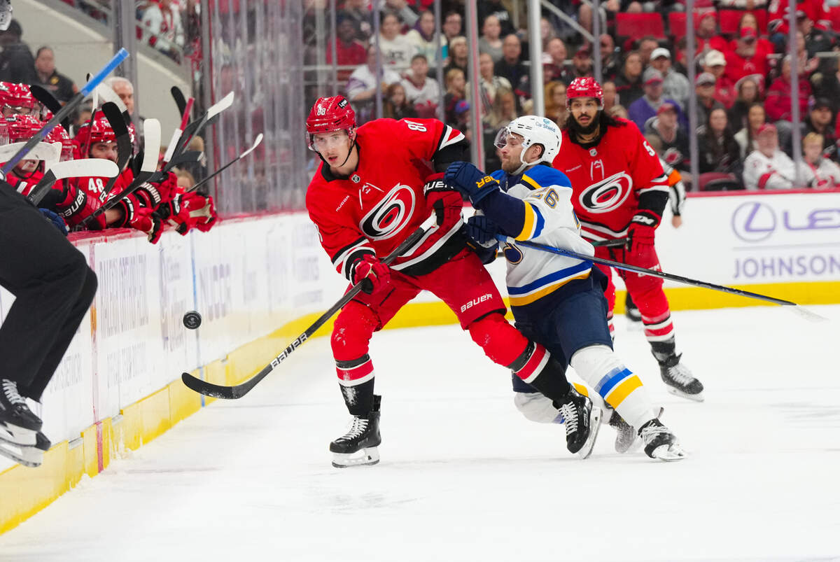 Nov 17, 2024; Raleigh, North Carolina, USA; St. Louis Blues left wing Nathan Walker (26) checks Carolina Hurricanes center Martin Necas (88) during the first period at Lenovo Center. Mandatory Credit: James Guillory-Imagn Images