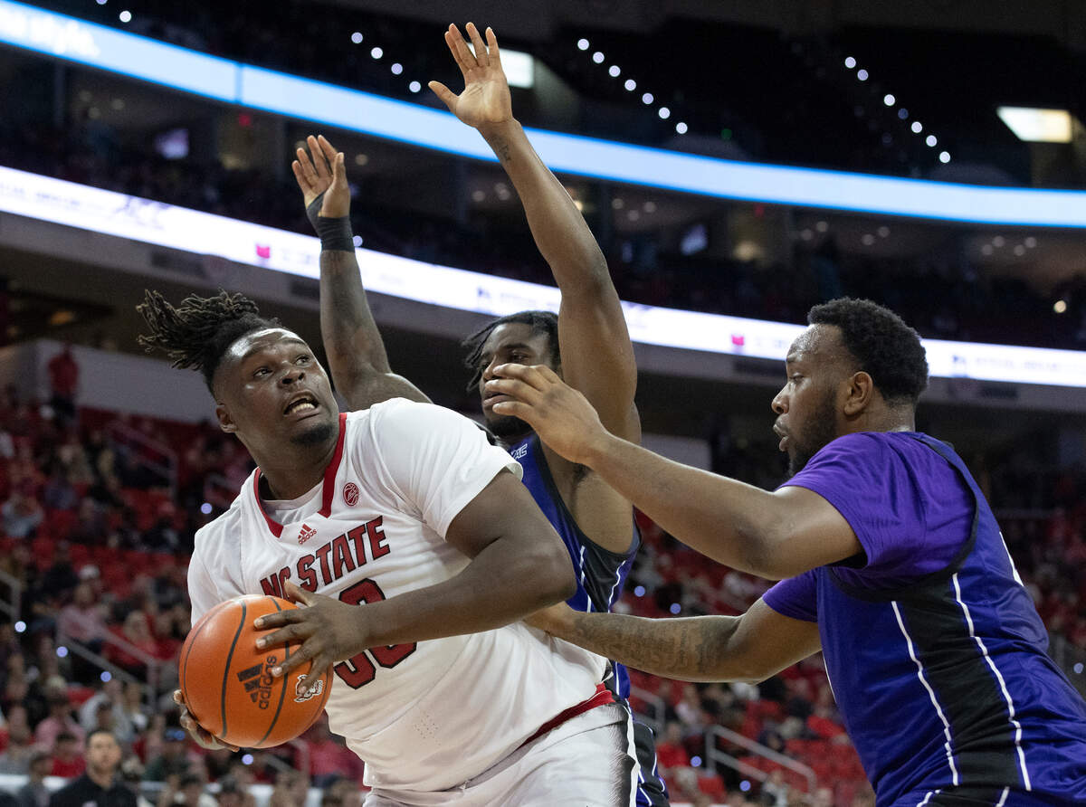 N.C. State’s DJ Burns Jr. looks to shoot over Abilene Christian’s Aidan Igiehon and Airion Simmons during the first half of the Wolfpack’s game on Friday, Nov. 10, 2023, at PNC Arena in Raleigh, N.C.