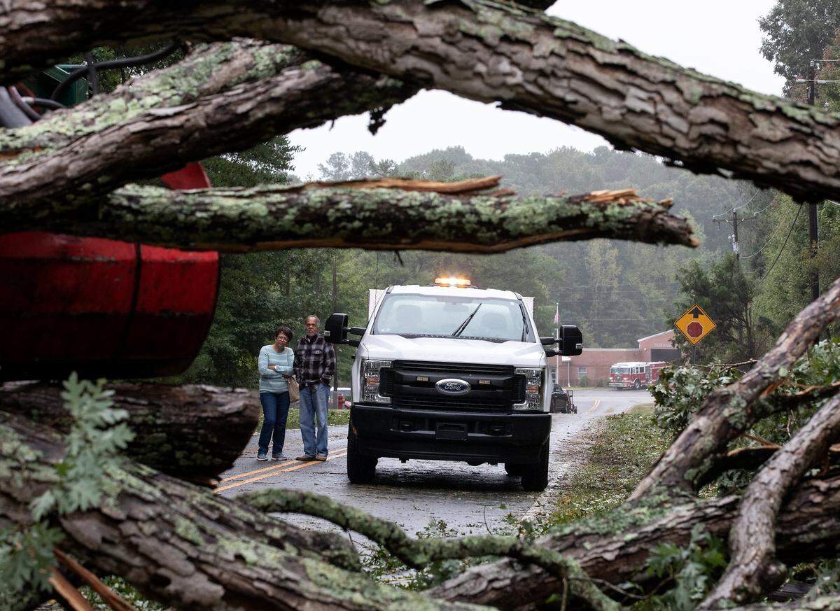 People watch as crews work to clear a downed tree blocking Bivins Road following Tropical Storm Ian on Saturday, Oct. 1, 2022, in Durham, N.C.