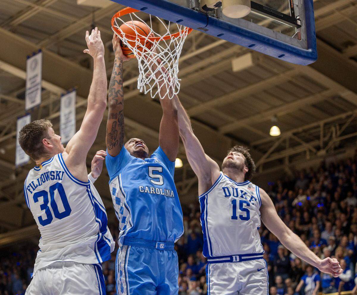 North Carolina’s Armando Bacot (5) muscles his way to the basket against Duke’s Kyle Filipowski (30) and Ryan Young (15) during the second half on Saturday, March 9, 2024 at Cameron Indoor Stadium in Durham, N.C.