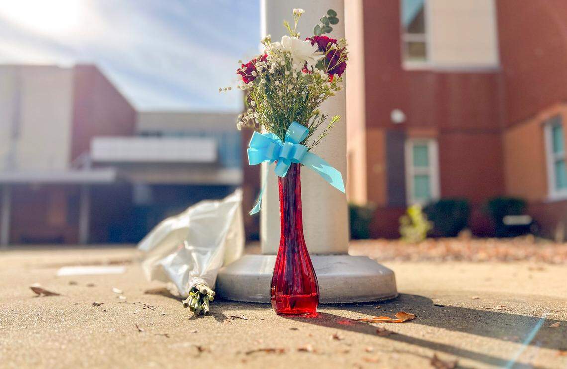 Flowers sit it at the base of a flagpole at Southeast Raleigh High School Tuesday morning, Nov 28, 2023. A 14-year-old has been charged with fatally stabbing a student and injuring another during a fight at the school on Monday morning.