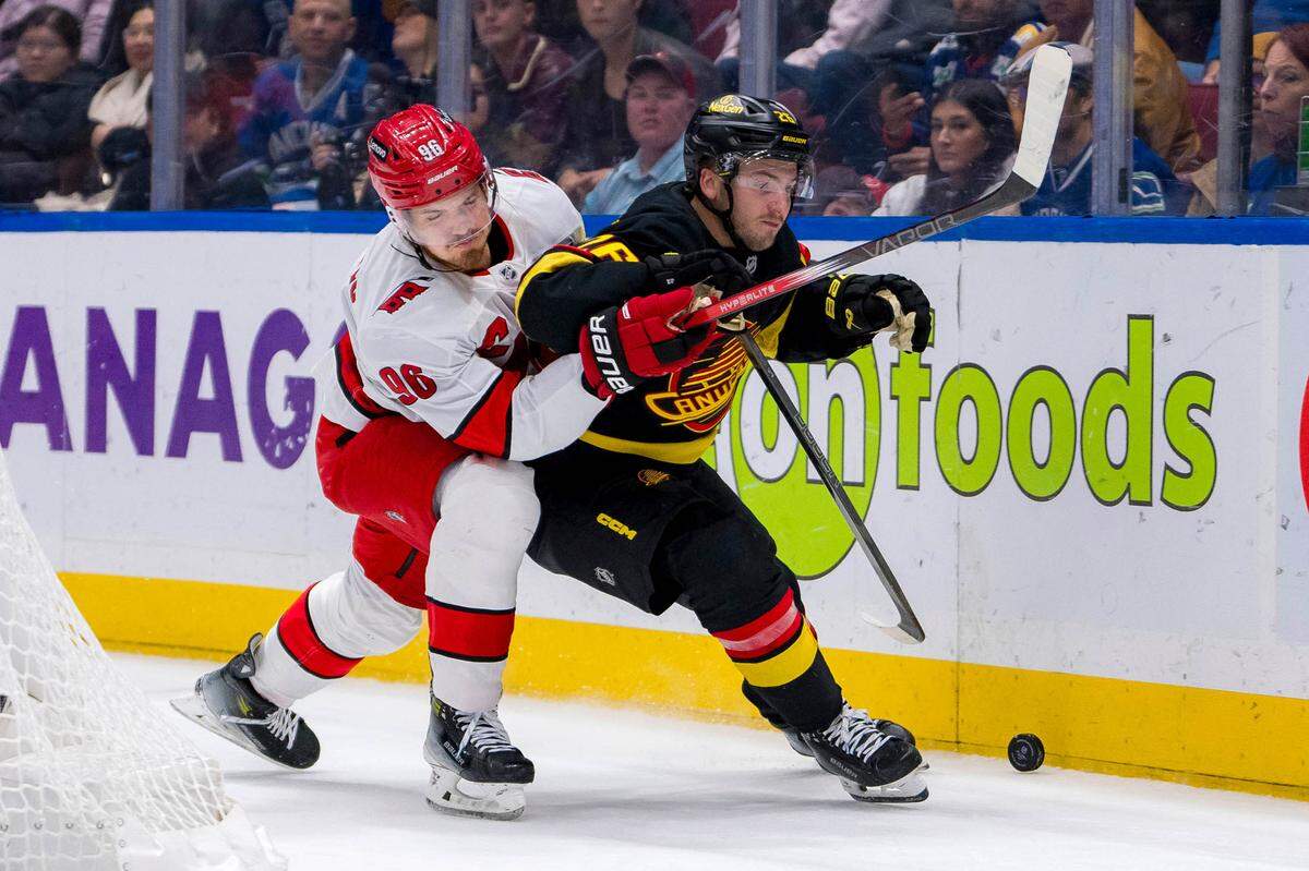 Oct 28, 2024; Vancouver, British Columbia, CAN; Carolina Hurricanes forward Jack Roslovic (96) checks Vancouver Canucks defenseman Erik Brannstrom (26) during the third period at Rogers Arena. Mandatory Credit: Bob Frid-Imagn Images