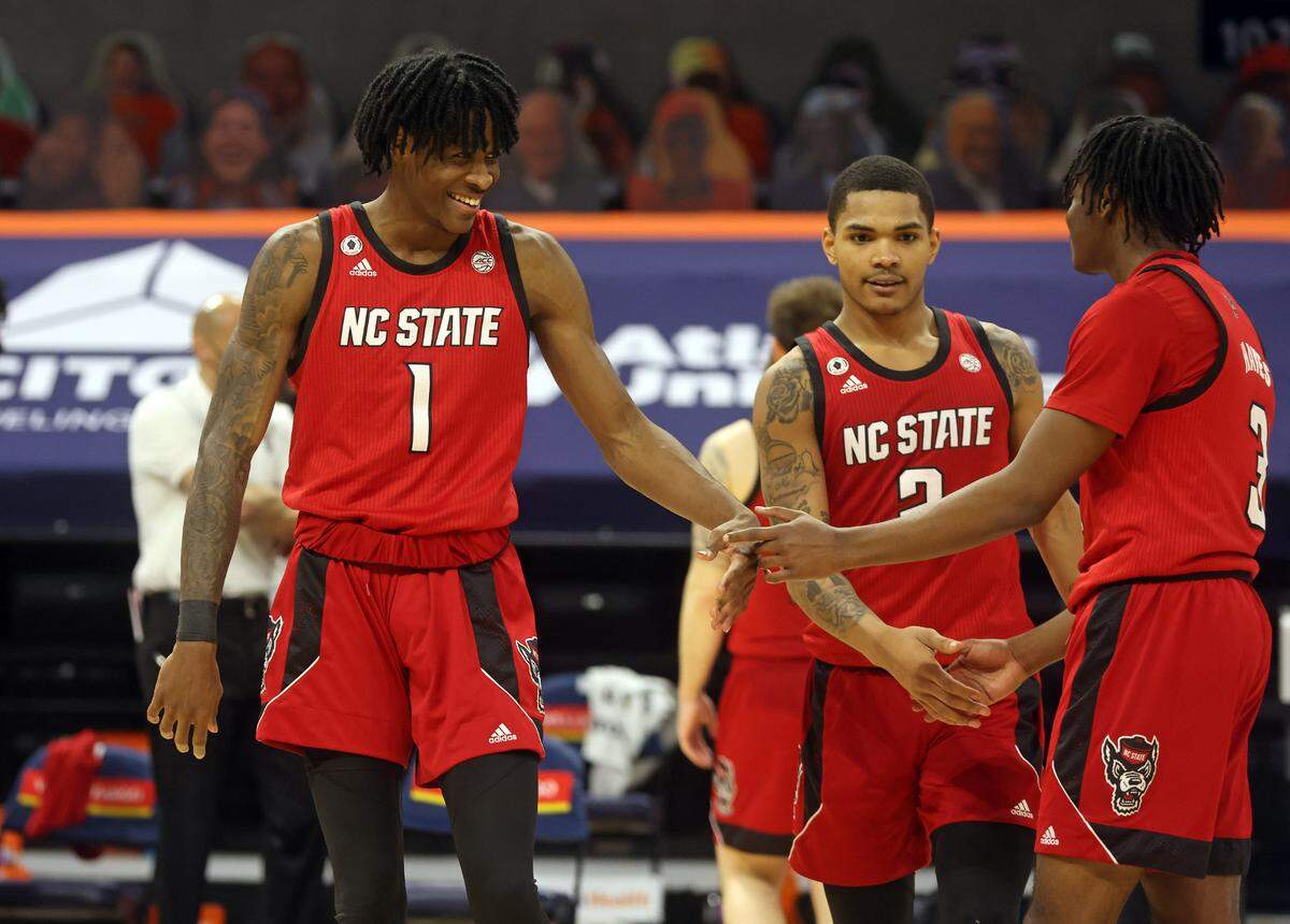 North Carolina State guard Dereon Seabron (1) celebrates with teammates North Carolina State guard Shakeel Moore (2) and North Carolina State guard Cam Hayes (3) during the game Wednesday in Charlottesville, Va. North Carolina State defeated Virginia 68-61.