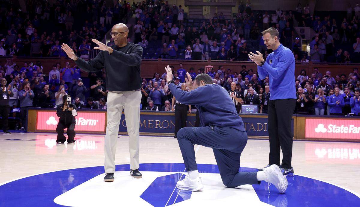 Former Duke head coach Mike Krzyzewski bows to UCF head coach Johnny Dawkins during a ceremony before Duke’s exhibition game against UCF at Cameron Indoor Stadium in Durham, N.C., Tuesday, Oct. 21, 2025. Duke head coach Jon Scheyer is to the right.