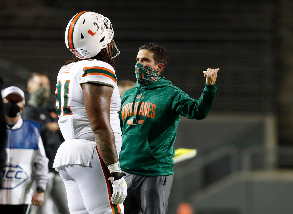Miami head coach Manny Diaz talks with defensive lineman Jordan Miller (91) during the first half of N.C. State’s game against Miami at Carter-Finley Stadium in Raleigh, N.C., Friday, Nov. 6, 2020.