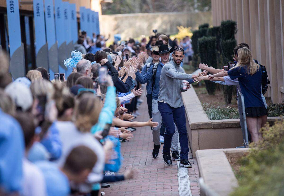 Ryan McAdoo leads the UNC menÕs basketball team past a line of excited fans outside the Dean Dome in Chapel Hill, N.C. as they start their journey to New Orleans to compete against Duke in the Final Four on Wednesday, March 30, 2022.