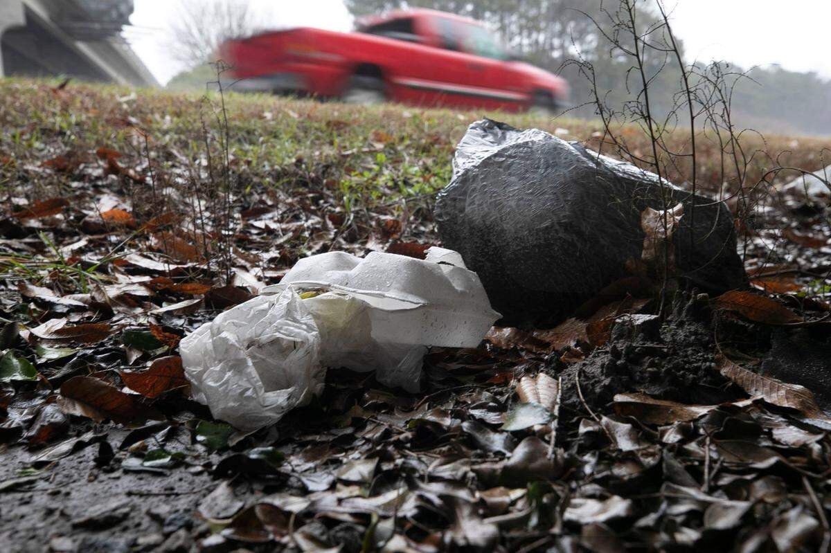 Traffic along Interstate 40 passes discarded food containers and a bag of trash at the North Harrison Avenue interchange in Cary on Feb. 5, 2021.