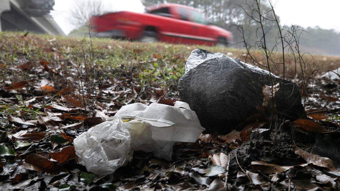 Traffic along Interstate 40 passes discarded food containers and a bag of trash at the North Harrison Avenue interchange on Friday, February 5, 2021, in Cary, N.C.