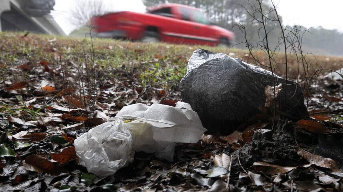 Traffic along I-40 passes discarded food containers and a bag of trash at the intersection with N. Harrison Ave. on Friday, February 5, 2021 in Cary, N.C.