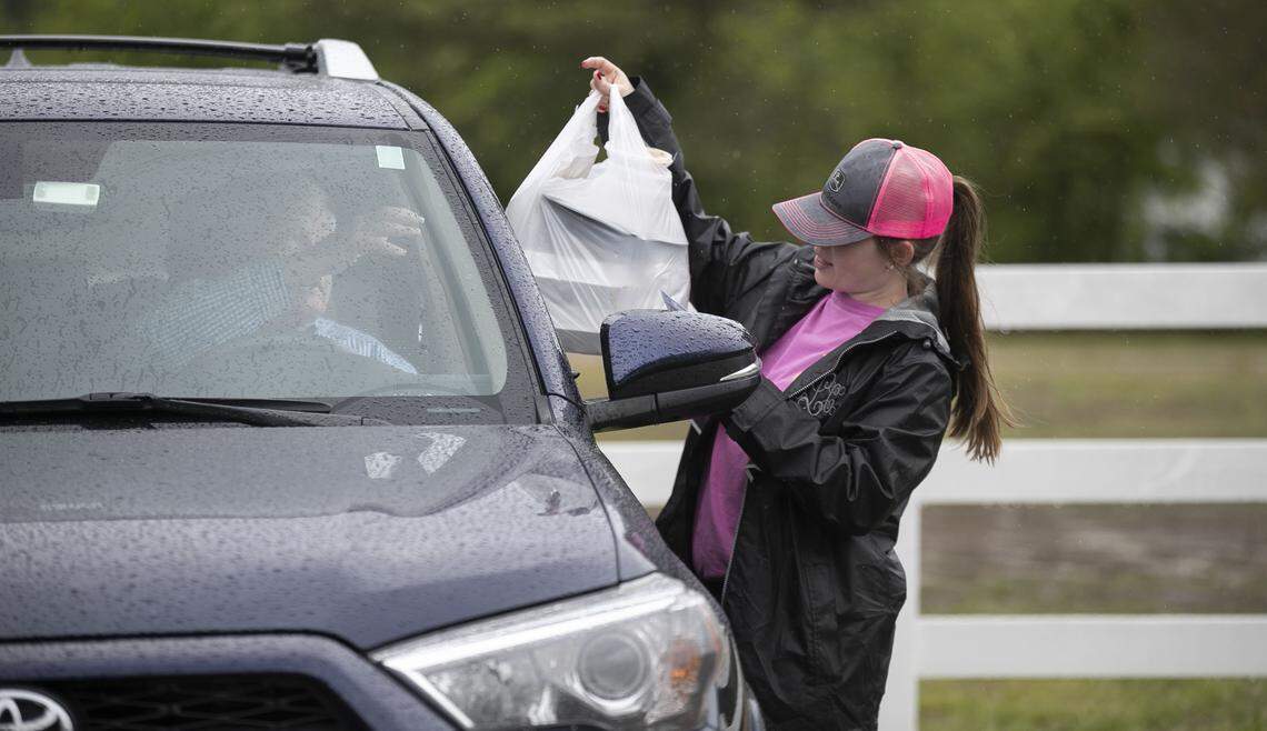 Cassie Langdon delivers a lunch order to a customer in their car at Angie’s Restaurant on Thursday, April 23, 2020 in Garner, N.C. With their popular dining room closed due to COVID-19 restrictions, the wait staff offers drive-in curb service. Customers can order from their cars, or phone in their orders.