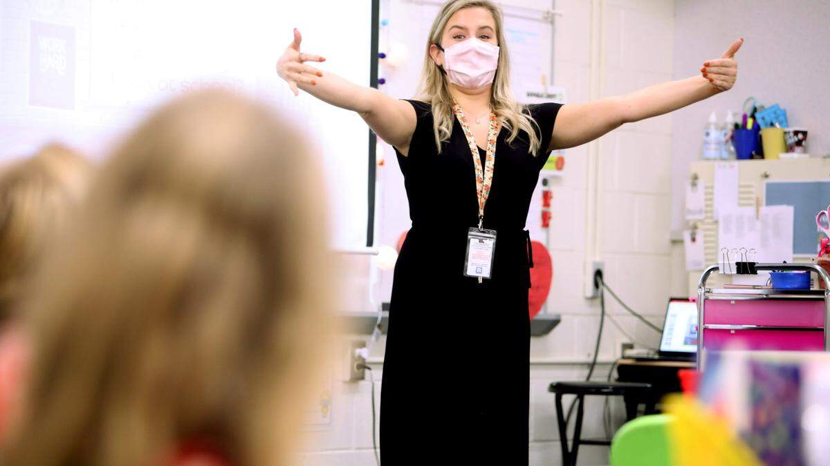Hunter Elementary School first-grade teacher Alyssa Housman demonstrates how to give an air hug to her class on Monday, October 26, 2020, on the first day back in school for some Wake students.