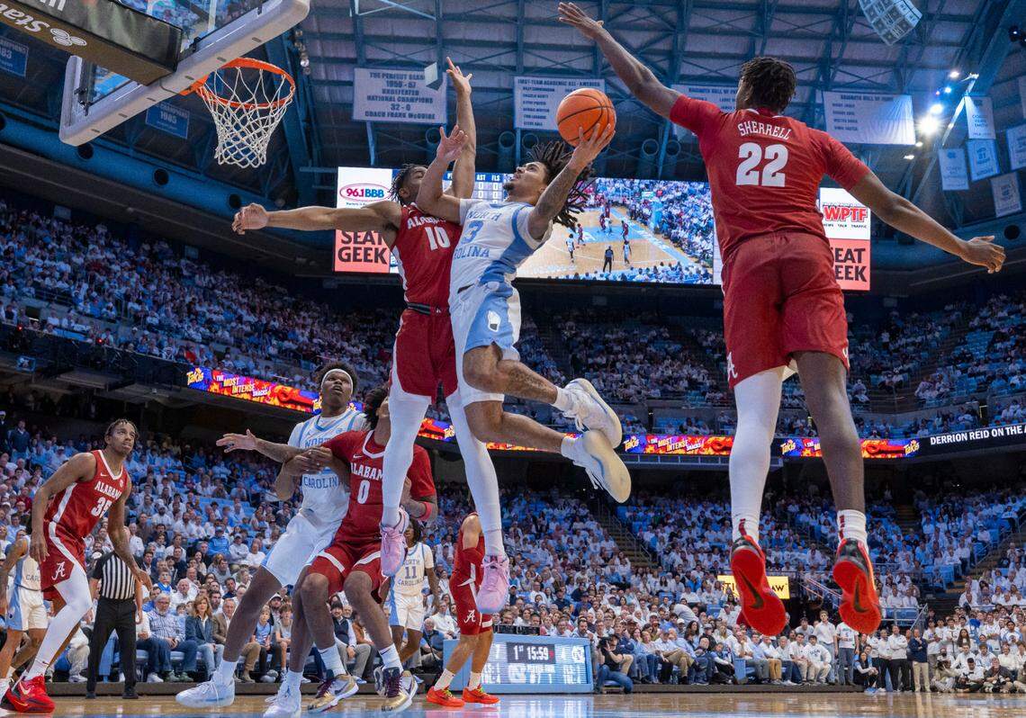 North Carolina guard Elliot Cadeau (3) drives to the basket between Alabama guard Labaron Philon (0) and forward Aiden Sherrill (22)in the first half on Wednesday, December 4, 2024 at the Smith Center in Chapel Hill, N.C.