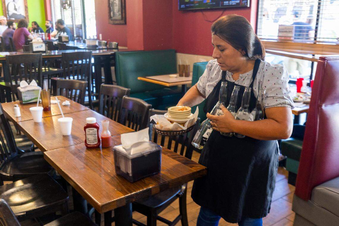 Edith Liborio busses tables in her restaurant the Esmeralda Grill on Friday, September 15, 2023 in Cary, N.C. Liborio also lives behind her business in the Chatham Estates mobile home park. Liborio is concerned about the loss of affordable housing, and her business space as her landlord who owns both is considering selling the properties.