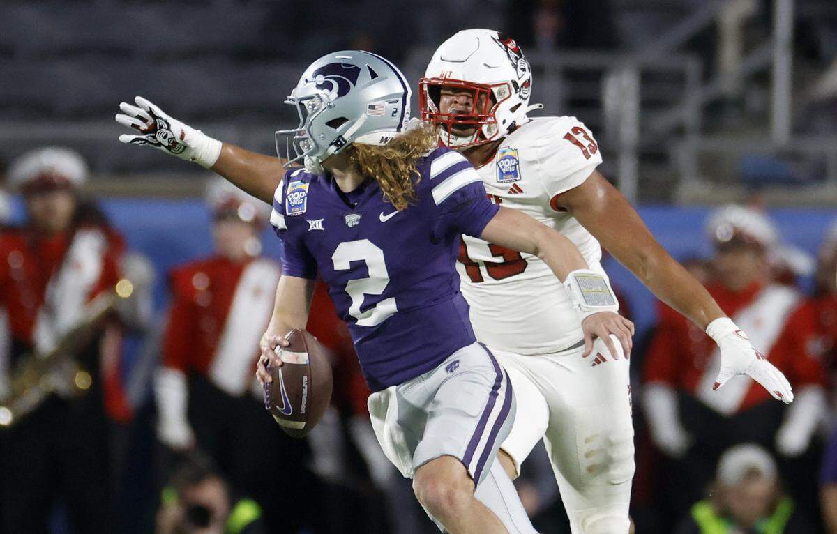 Kansas State quarterback Jake Rubley (2) escapes from N.C. State defensive end Travali Price (13) during the first half of N.C. State’s game against Kansas State in the Pop-Tarts Bowl at Camping World Stadium in Orlando, Fla., Thursday, Dec. 28, 2023.