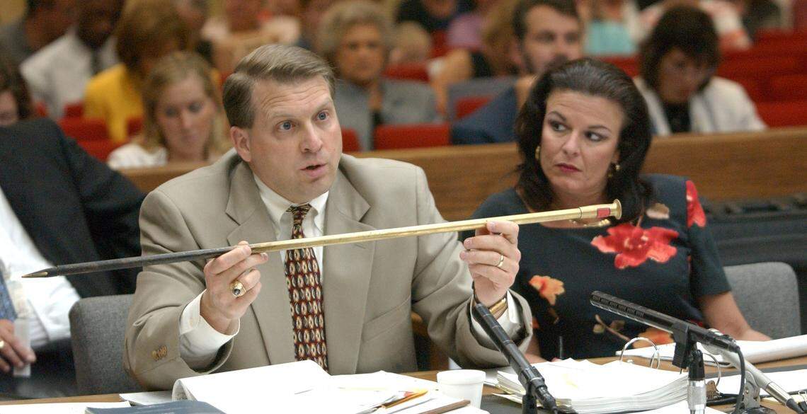 Prosecutor Jim Hardin (left) holds up a brass blow poker, identical to one given to the Michael Peterson family but then missing from the Peterson homeProsecutor Freda Black is at right. Hardin was questioning expert witness Dr. Deborah Radisch about blunt trauma injuries and if the type of poker he was holding would cause such injuries.