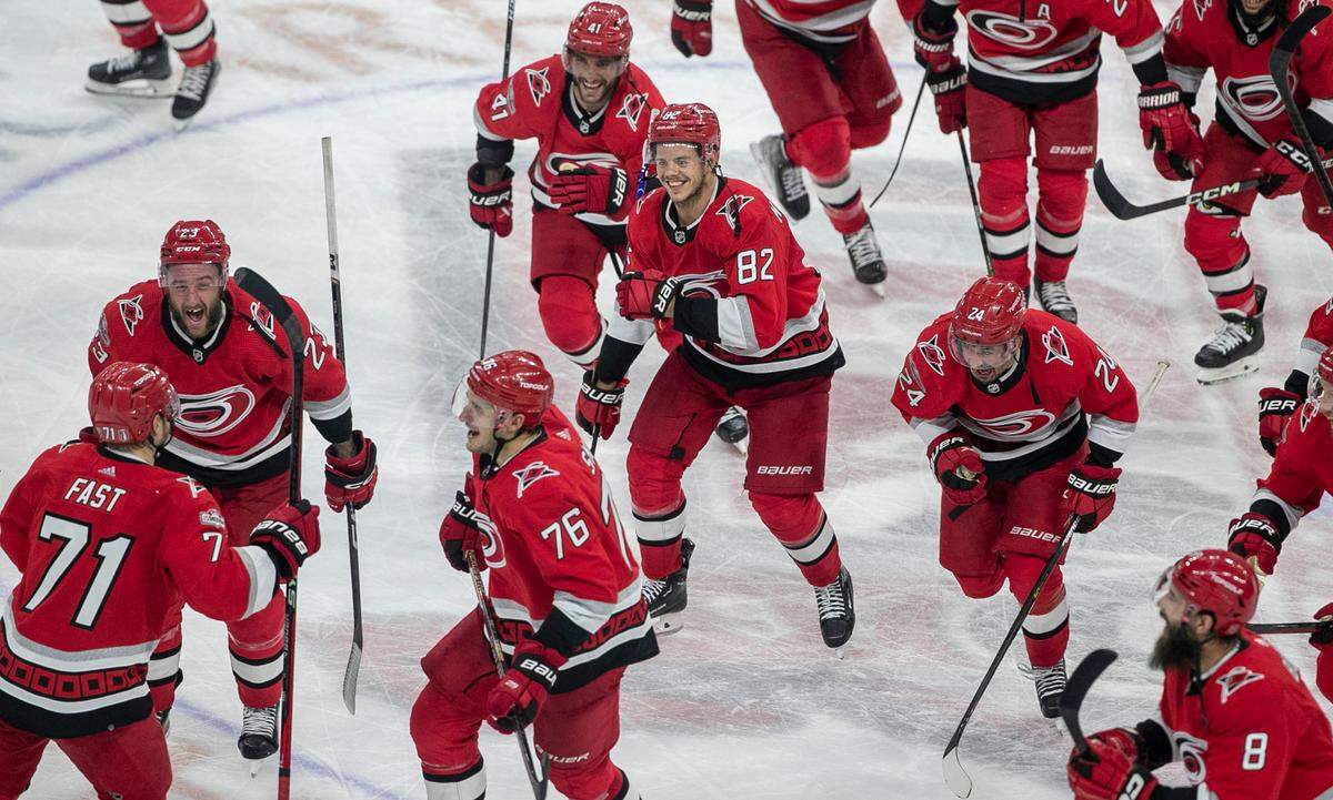 The Carolina Hurricanes swarm to Jesper Fast (71) during their post-game celebration after Fast scored the game winning goal in overtime to secure a 3-2 victory over the New Jersey Devils, clinching their second round Stanley Cup series on Thursday, May 11, 2023 at PNC Arena in Raleigh, N.C.