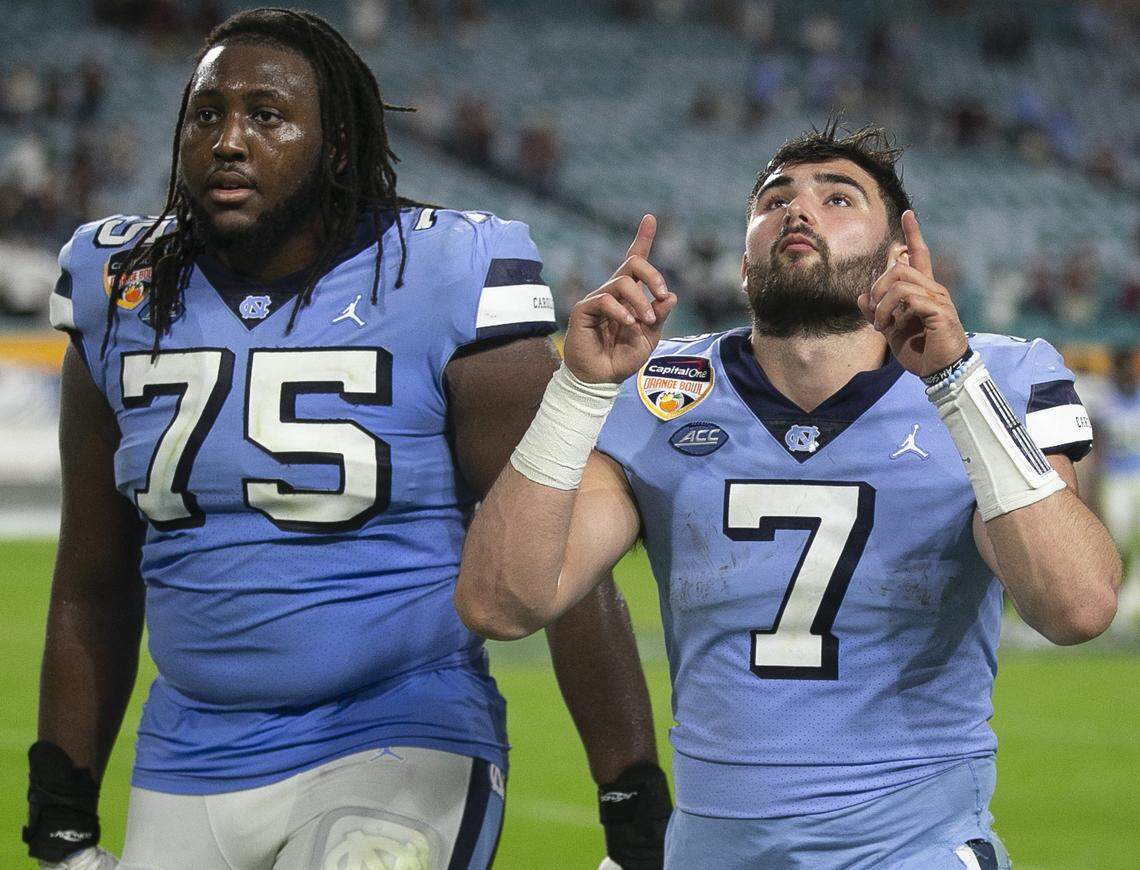 North Carolina’s Joshua Ezeudu (75) and quarterback Sam Howell leave the field following the Tar Heels’ 41-27 loss to Texas A&M in the Capital One Orange Bowl on Jan. 2 in Miami Gardens, Fla.