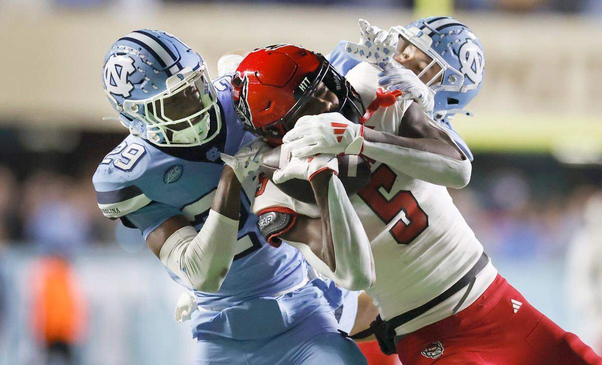 N.C. State wide receiver Noah Rogers (5) pulls in a 44-yard reception while being defended North Carolina’s Marcus Allen (29) and Will Hardy (31) late in the fourth quarter of N.C. State’s 35-30 victory over UNC at Kenan Stadium in Chapel Hill, N.C., Saturday, Nov. 30, 2024.
