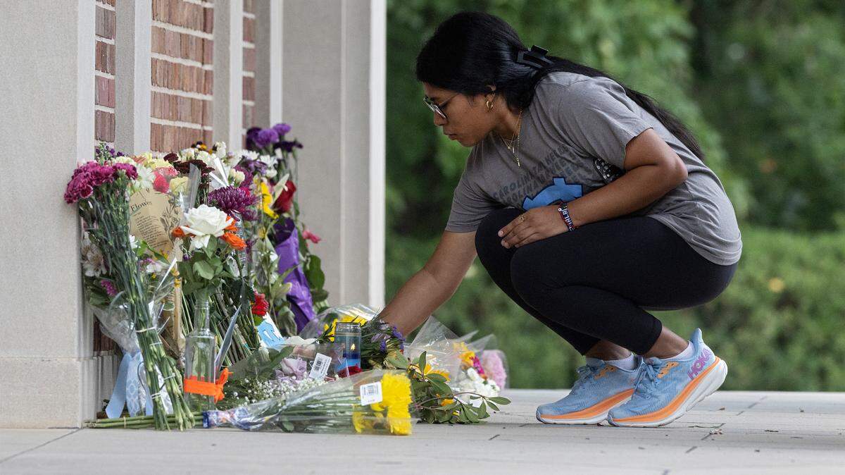 Ashley Vicente Lopez, a first-year student at UNC-Chapel Hill, leaves flowers at a memorial at the base of the bell tower on Wednesday, Aug. 30, 2023, in Chapel Hill, N.C. after professor Zijie Yan was killed in a shooting on campus.