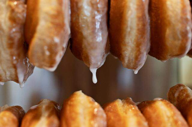 Fresh hot glaze drips off the donuts at Bright Spot Donuts on Friday, March 18, 2022. The new Raleigh donut shop will open soon near the Five Points Neighborhood.