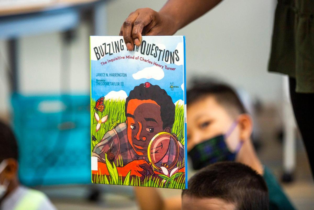 Bria Wright shows the cover of a book about Charles Henry Turner, a zoologist and the first African American to receive a graduate degree at the University of Cincinnati in 1892, to her second grade class at Hortons Creek Elementary School, on May 6, 2021, in Cary, N.C. It’s part of how Wake County schools says it’s trying to promote diversity, equity and inclusion in classrooms.