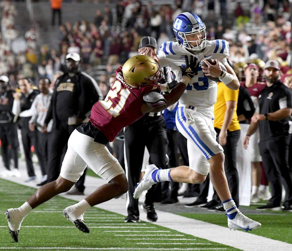 Duke quarterback Riley Leonard, right, is shoved out of bounds by Boston College defenseman Josh DeBerry (21) during the second half of an NCAA college football game Friday, Nov. 4, 2022, in Boston. (AP Photo/Mark Stockwell)