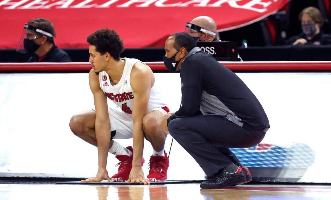 N.C. State’s head coach Kevin Keatts crouches next to Jericole Hellems (4) as Hellems waits to enter the game during the second half of N.C. State’s 69-50 victory over Campbell at PNC Arena in Raleigh, N.C., Saturday, Dec. 19, 2020.