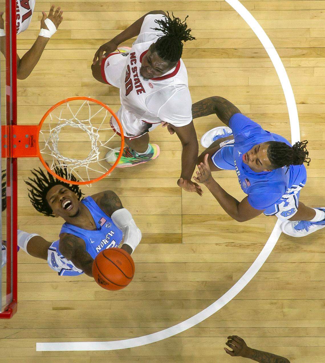 North Carolina’s Caleb Love (2) drives past N.C. State’s D.J. Burns (30) for a reverse layup during the second half on Sunday, February 19, 2023 at PNC Arena in Raleigh, N.C. Love lead the Tar Heels with 23 points in their 77-69 loss.