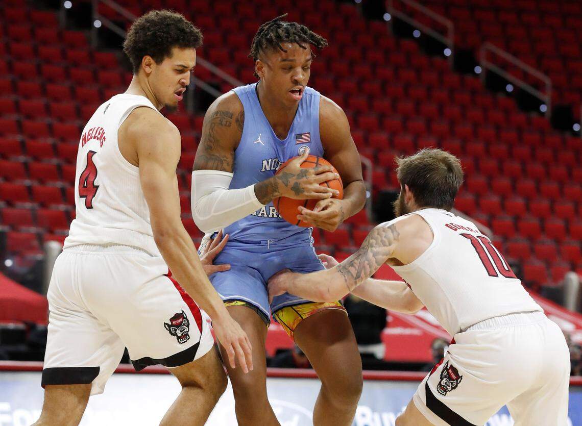 North Carolina’s Armando Bacot (5) keeps the ball from N.C. State’s Jericole Hellems (4) and Braxton Beverly (10) during the second half of N.C. State’s 79-76 victory over UNC at PNC Arena in Raleigh, N.C., Tuesday, December 22, 2020.