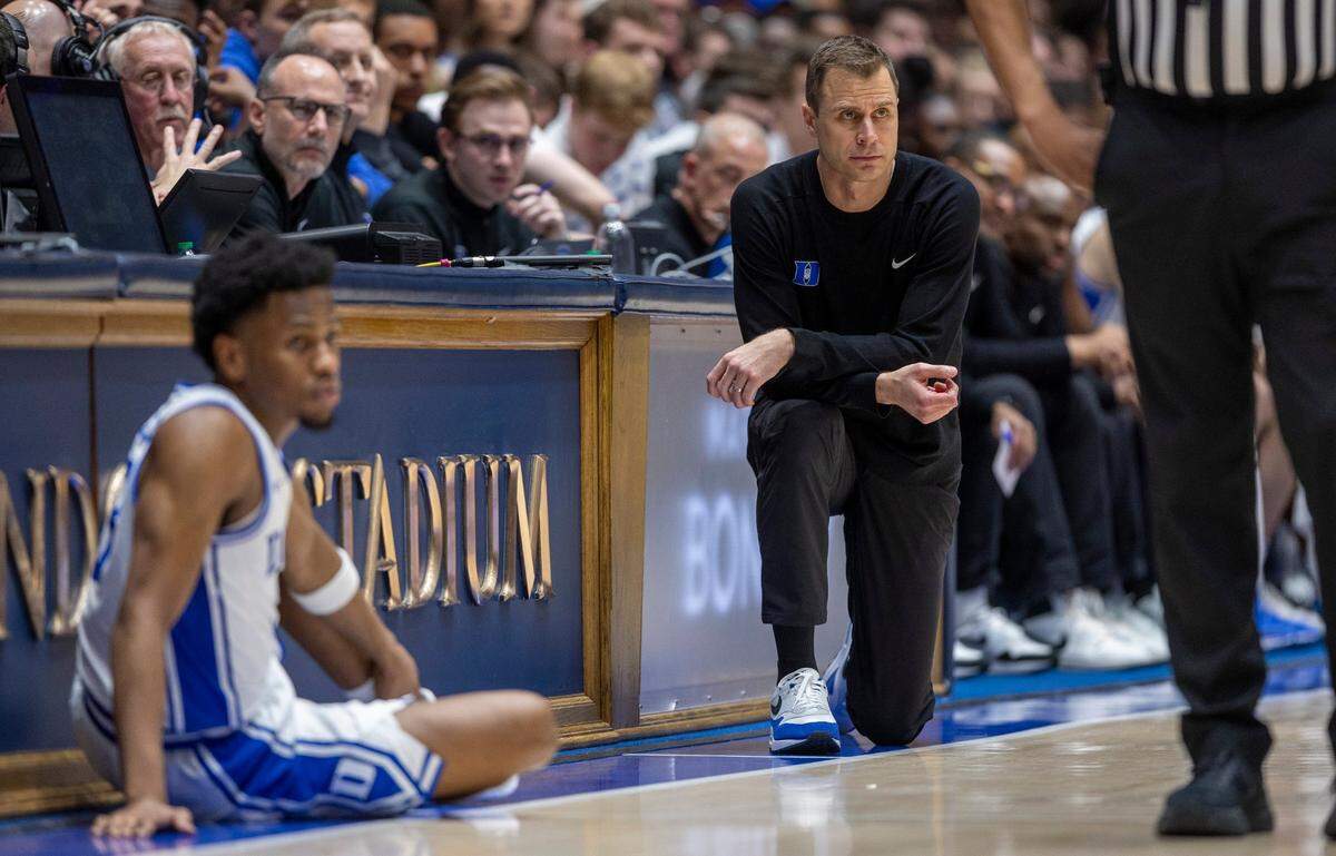 Duke coach Jon Scheyer takes a knee as Jeremy Roach (3) waits to enter the game in the first half against North Carolina on Saturday, March 9, 2024 at Cameron Indoor Stadium in Durham, N.C.
