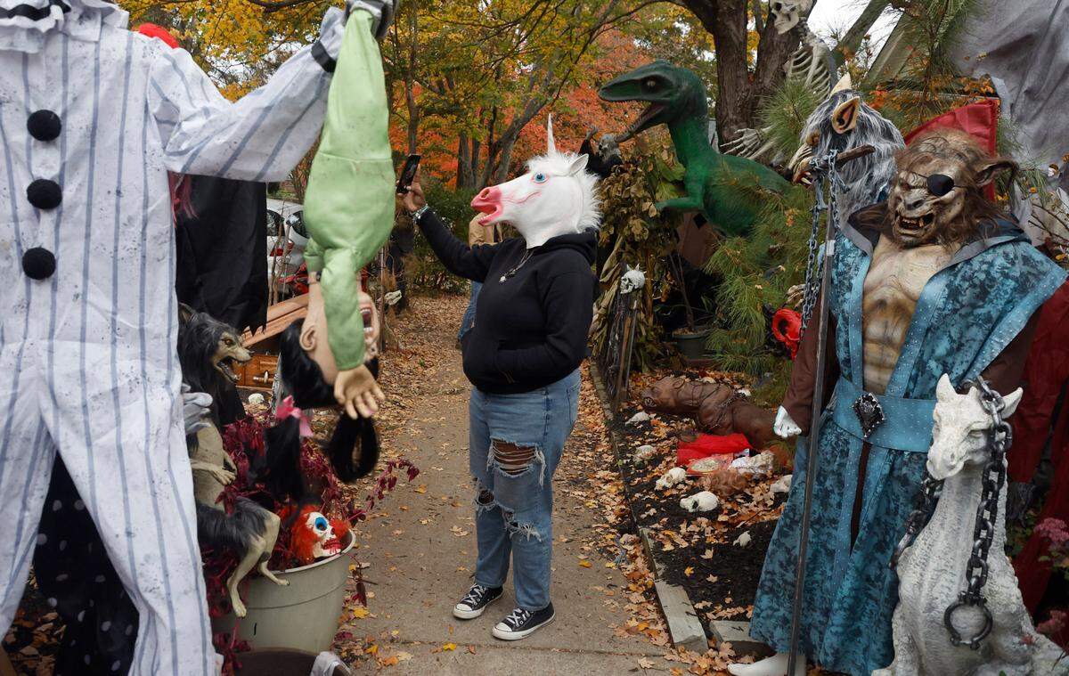 Arielle Jackson takes her photo outside the Oakwood home of Jesse Jones Friday, Oct. 28, 2022. More than 50 full-sized monsters are set up in Jones’ yard bringing thousands of visitors on Halloween.