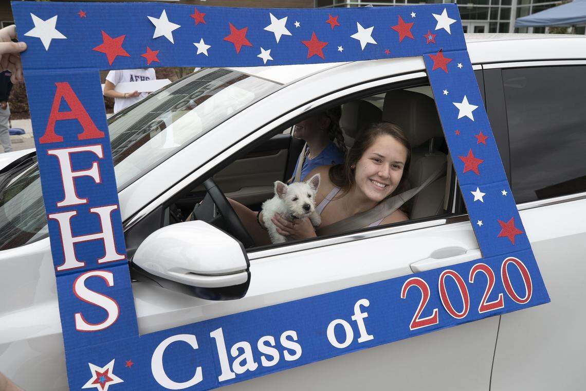 Apex Friendship High School senior Haley Turner stops to have his photograph taken by faculty after picking up his cap and gown on Tuesday May 5, 2020 in Apex, N.C. Principal Matt Wight orchestrated a drive-thru celebration with more than 60 faculty and staff participating. The celebration featured music, cheers and some tears for the graduating class.