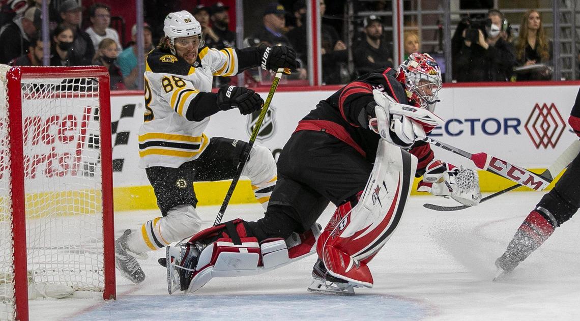 Boston Bruins’ David Pastrnak (88) checks Carolina Hurricanes’ goalie Antii Raanta (32) to the ice in the first period on Wednesday, May 4, 2022 during game two of their Stanley Cup first round series at PNC Arena in Raleigh, N.C. Antii was injured and left the game.
