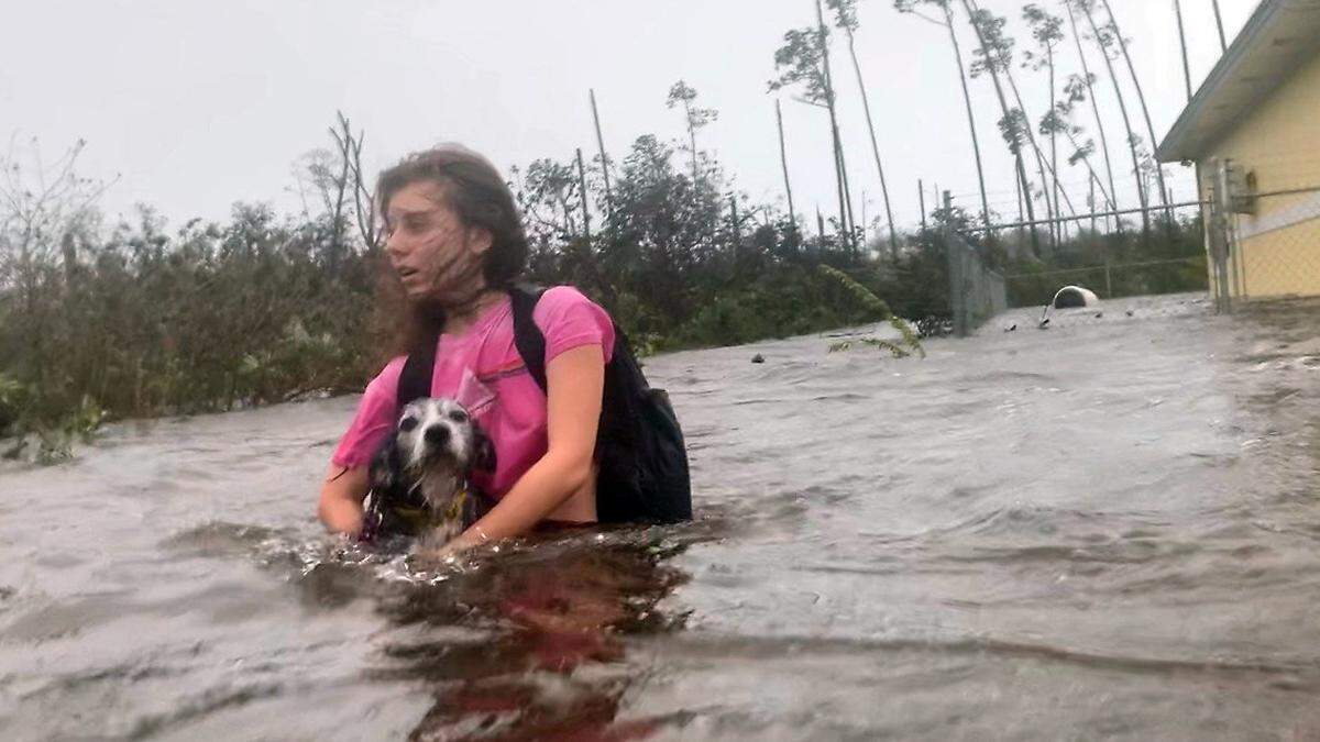 Julia Aylen camina por el agua hasta la cintura cargando a su perro mientras es rescatada de su casa inundada durante el huracán Dorian en Freeport, Bahamas, el martes 3 de septiembre de 2019.