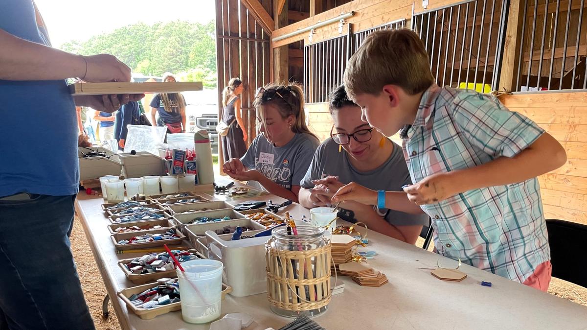 Ben Winkler, 8, consults with a Kidzu volunteer while crafting a mosaic from small tile chips at one of the educational stations for Kidzu’s June 2 Summerfest, held to show off its future N.C. Children’s Museum site on Mt. Carmel Church Road in Chapel Hill.