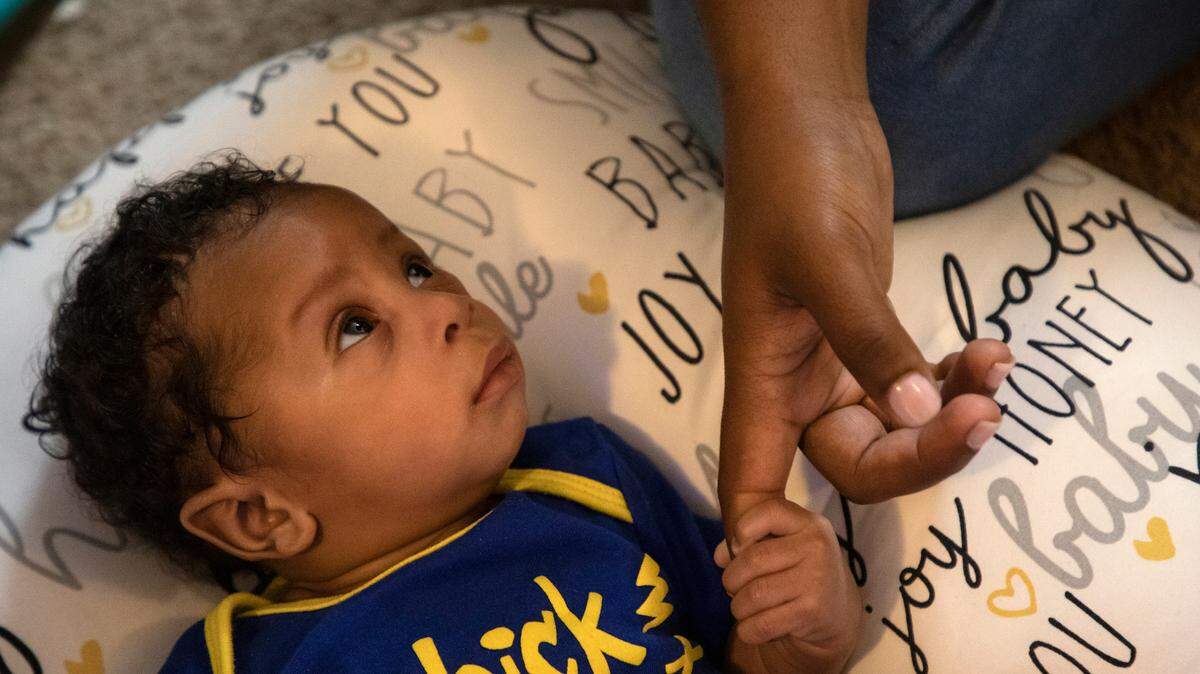 Two-month-old Amillion Gaston holds the hand of his mother, Eshawney Gaston, in Durham, N.C. on Wednesday, May 18, 2022.