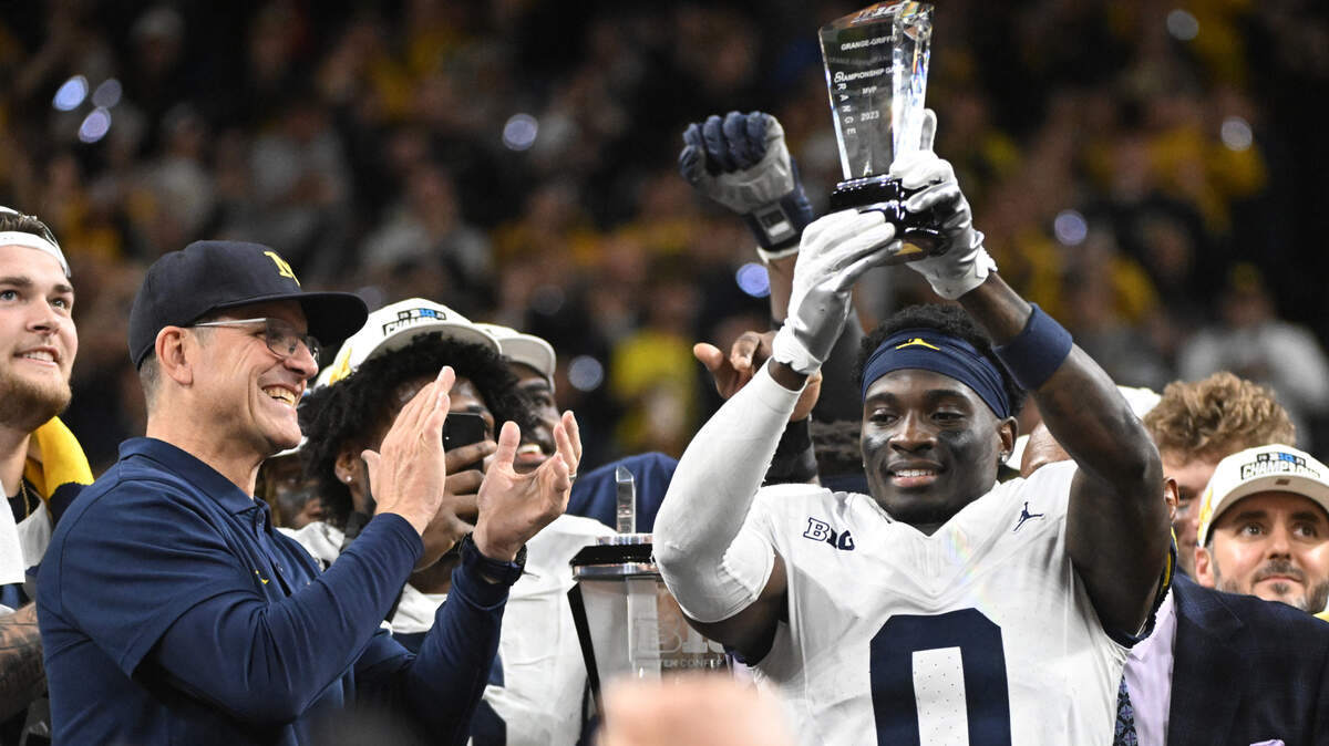 Dec 2, 2023; Indianapolis, IN, USA; Michigan Wolverines head coach Jim Harbaugh celebrates with MVP defensive back Mike Sainristil (0) after winning the Big Ten Championship game against the Iowa Hawkeyes at Lucas Oil Stadium.