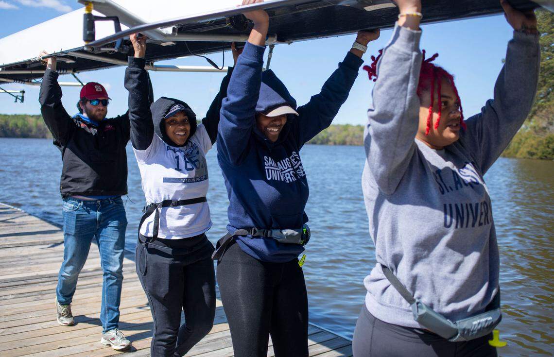 From left, Kees Koopman, Destini “Dee” Vance, Breanna Dorway, and Mikahya Hill carry a rowing shell off a dock on Lake Wheeler in Raleigh, N.C. after crew practice on Sunday April 10, 2022.