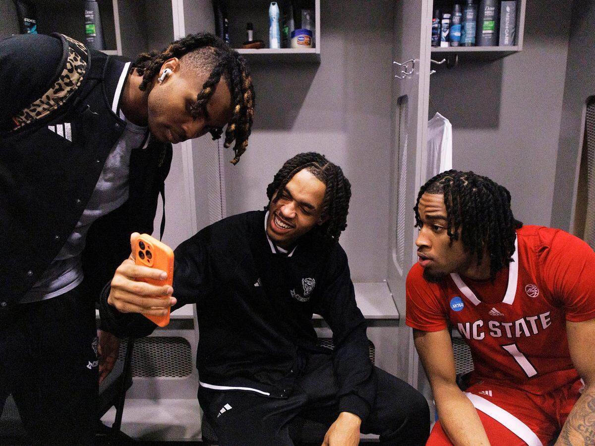 N.C. State’s Kam Woods, Breon Pass and Jayden Taylor watch video of celebrations at the N.C. State Memorial Belltower following the Wolfpack’s 67-58 win over Marquette in the NCAA Tournament Sweet 16 on Friday, March 29, 2024, at American Airlines Center in Dallas, Texas.
