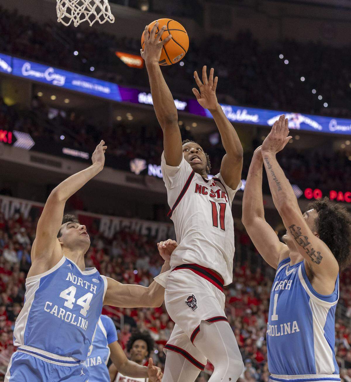 N.C. State guard Quadir Copeland (11) drives to the basket between North Carolina guard Luka Bogavac (44) and center Zayden High (1) in the first half on Tuesday, February 17, 2026 at Lenovo Center in Raleigh, N.C.