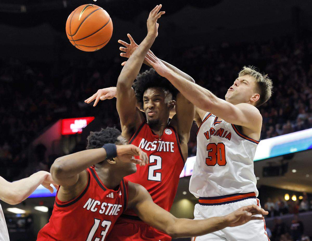 N.C. State's Musa Sagnia and Paul McNeil Jr. battle for a rebound with Virginia's Dallin Hall during the second half of the Wolfpack’s 90-61 loss on Thursday, Feb. 24, 2026, at John Paul Jones Arena in Charlottesville, Va. 